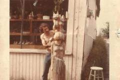 John carving a statute of SueAnn with one of their cats on her head.
